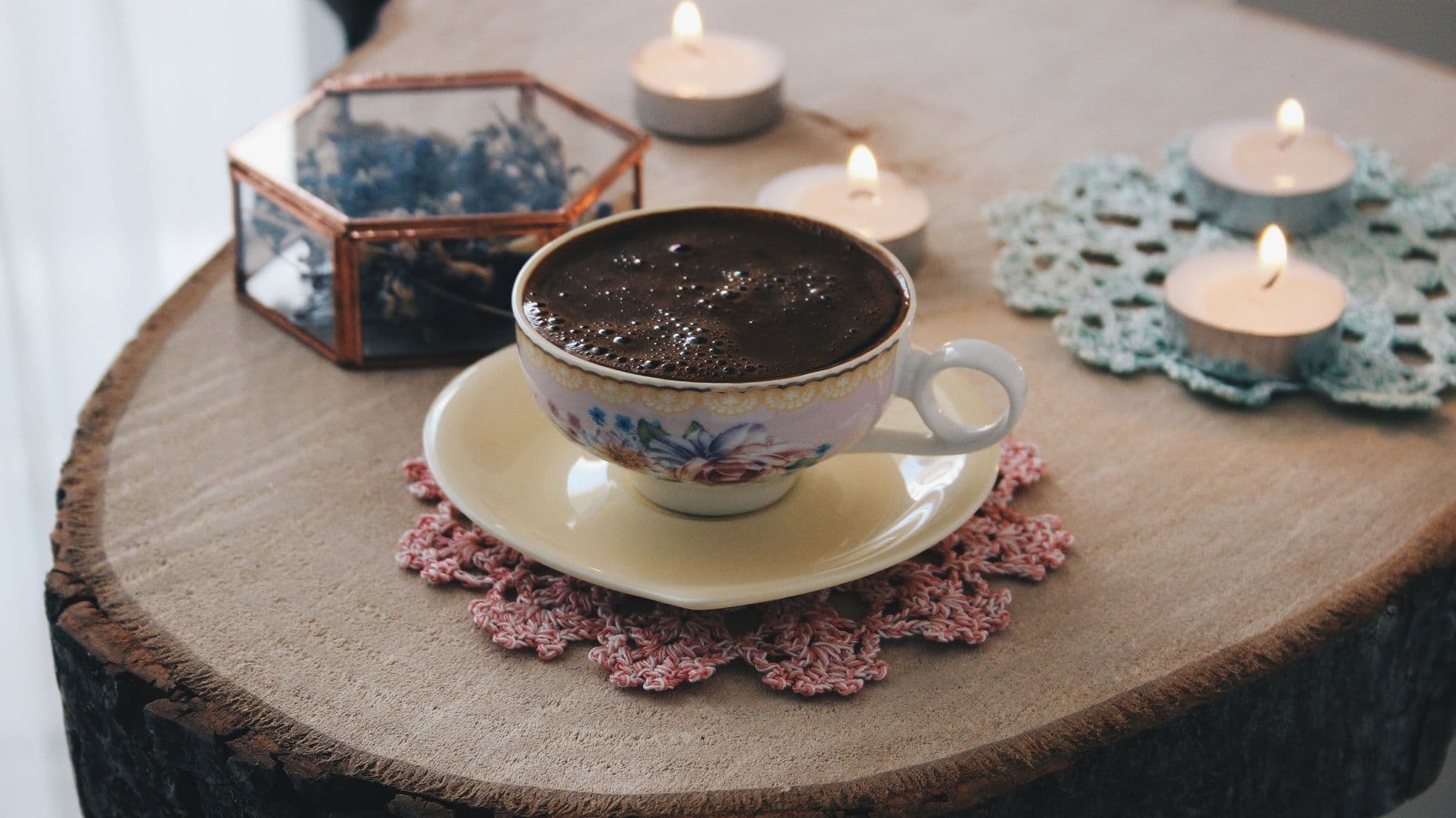 A cup of coffee and lit candles on a wooden table